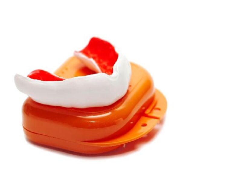 A white and red mouthguard placed on top of an orange case, typically used in sports to protect teeth and gums from injury.